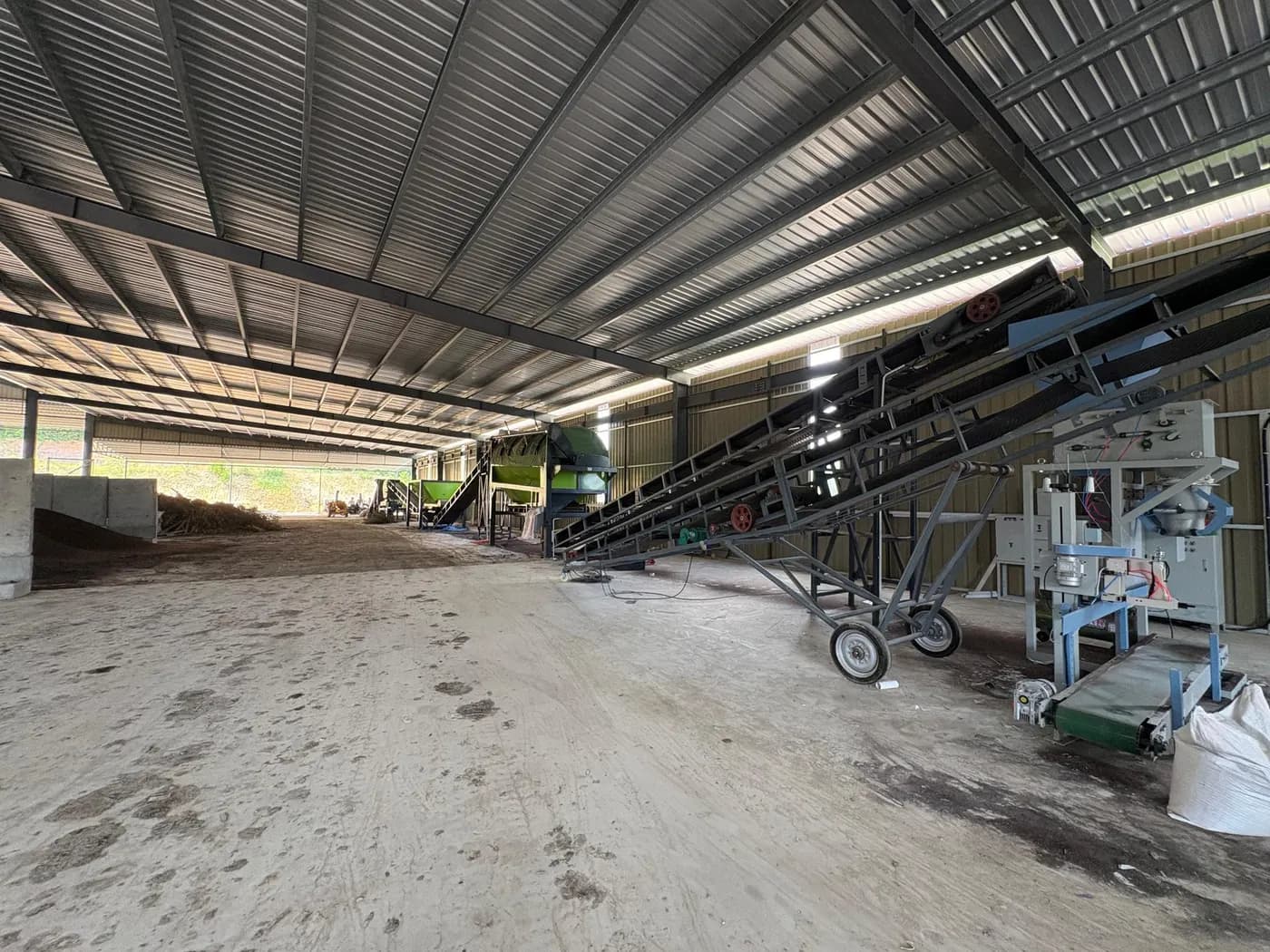 The fermentation production line, with a yellow mixer, blue tanks and pumps on a concrete floor where organic waste is blended into substrate